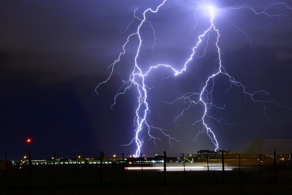 3 major veins of purple lightning striking down on a city scape in the distance